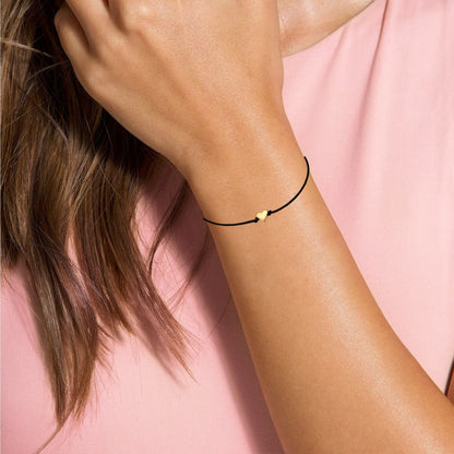 Dabble Doll Gold heart bracelet on a woman's wrist with a black cord, perfect for girls and ladies