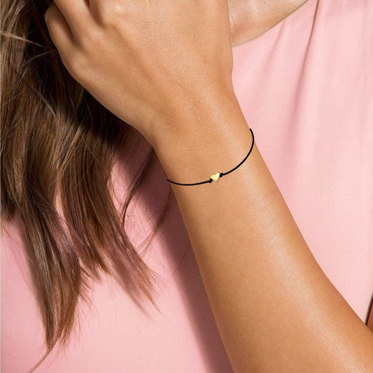 Dabble Doll Gold heart bracelet on a woman's wrist with a black cord, perfect for girls and ladies