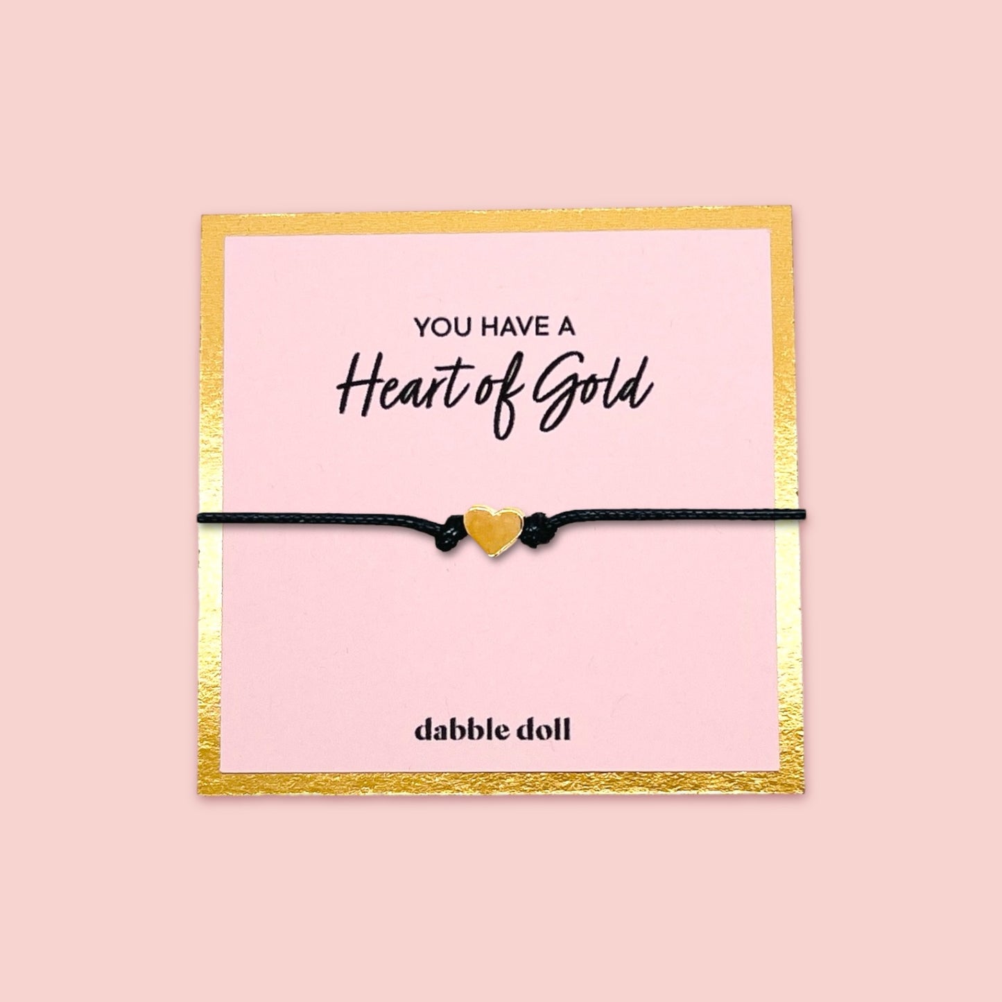 Dabble Doll heart bracelet gift box featuring a gold heart charm on a black cord, perfect for girls and women