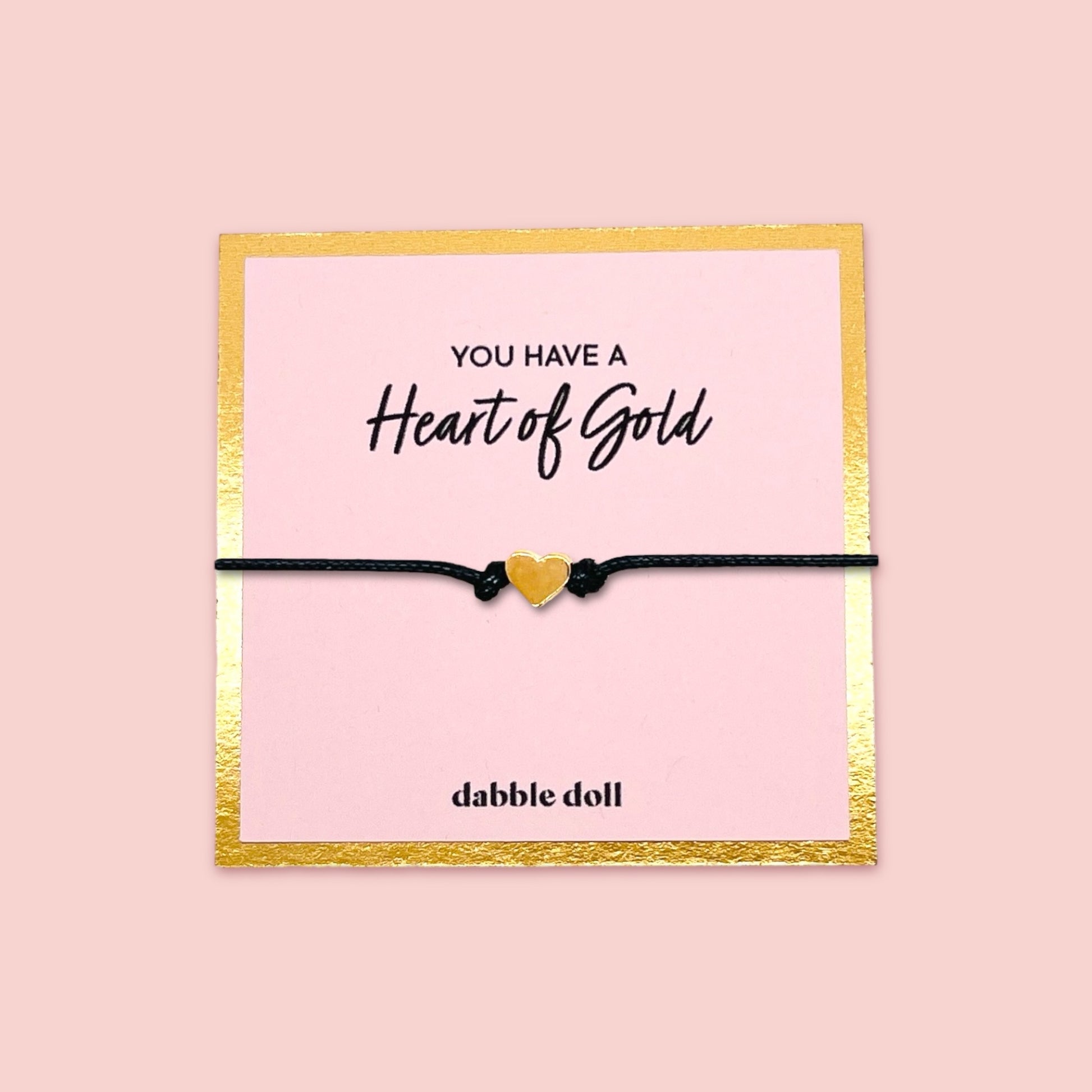 Dabble Doll heart bracelet gift box featuring a gold heart charm on a black cord, perfect for girls and women