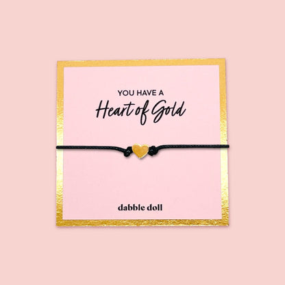 Dabble Doll heart bracelet gift box featuring a gold heart charm on a black cord, perfect for girls and women