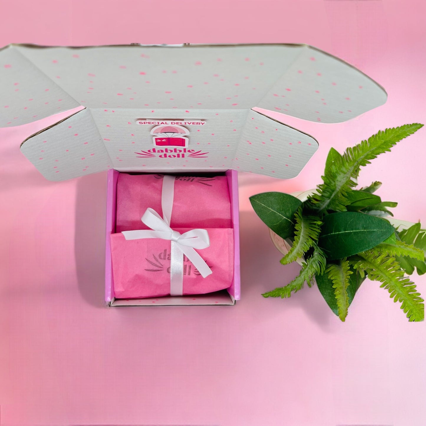 Dabble Doll pink packaged gift box for girls featuring a delicate bow, representing success with stylish presentation