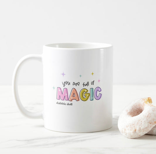 Dabble Doll magic mug featuring colorful text saying you are full of magic next to a donut