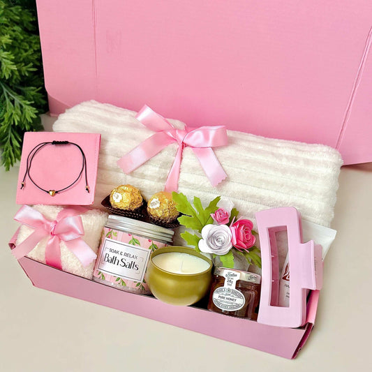Dabble Doll pink relaxation care package gift box with bath salts, candle, cozy socks, chocolates, and floral decor