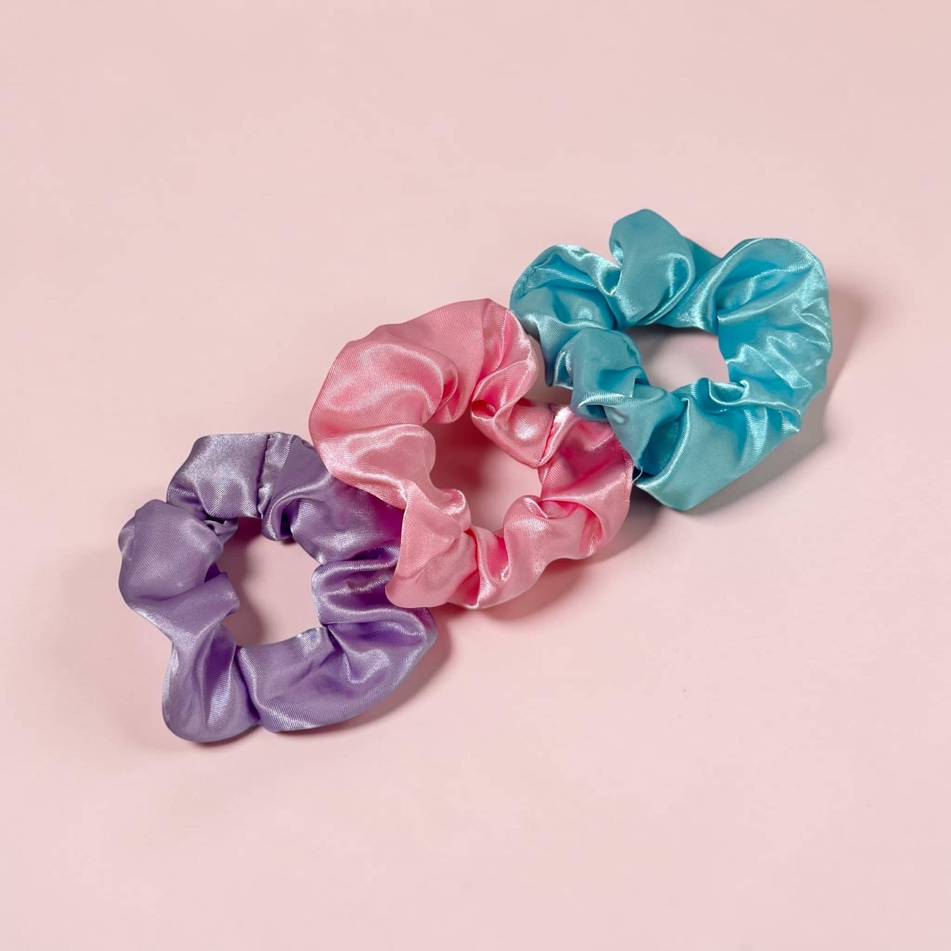 Set of three satin scrunchies in lavender, pink, and teal by Dabble Doll for stylish hair accessories