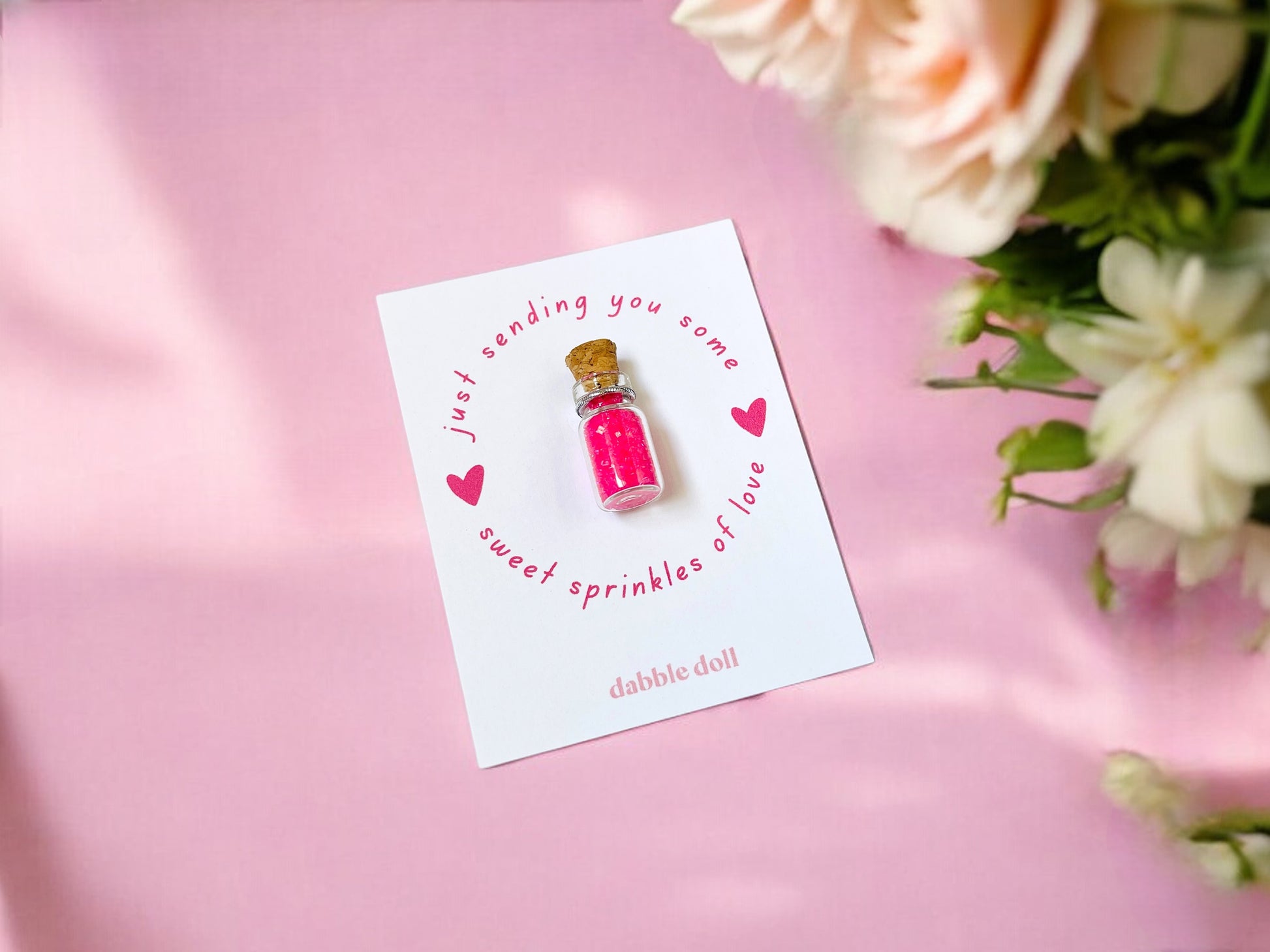 Pink Dabble Doll sprinkles in a glass vial on a card, perfect for girls and women crafting projects