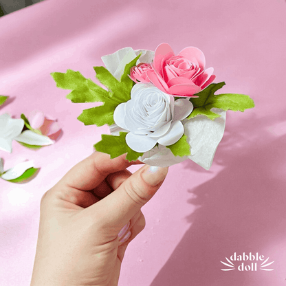 Hand holding delicate pink and white paper flowers with green leaves for thinking of you care package for women
