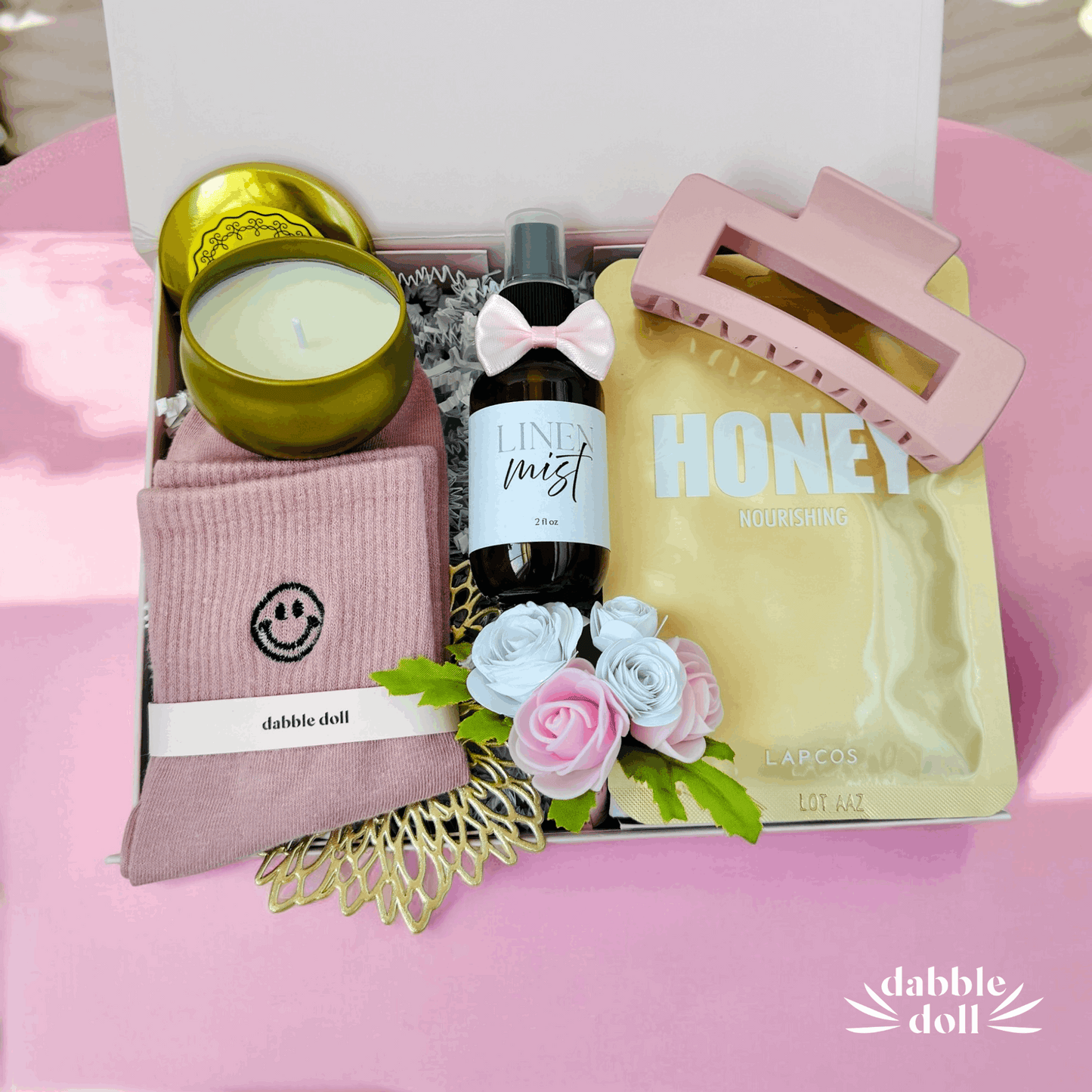 Dabble Doll gift box with unique relaxation gift ideas including candle, linen mist, hair clip, nourishing honey mask, and cozy socks