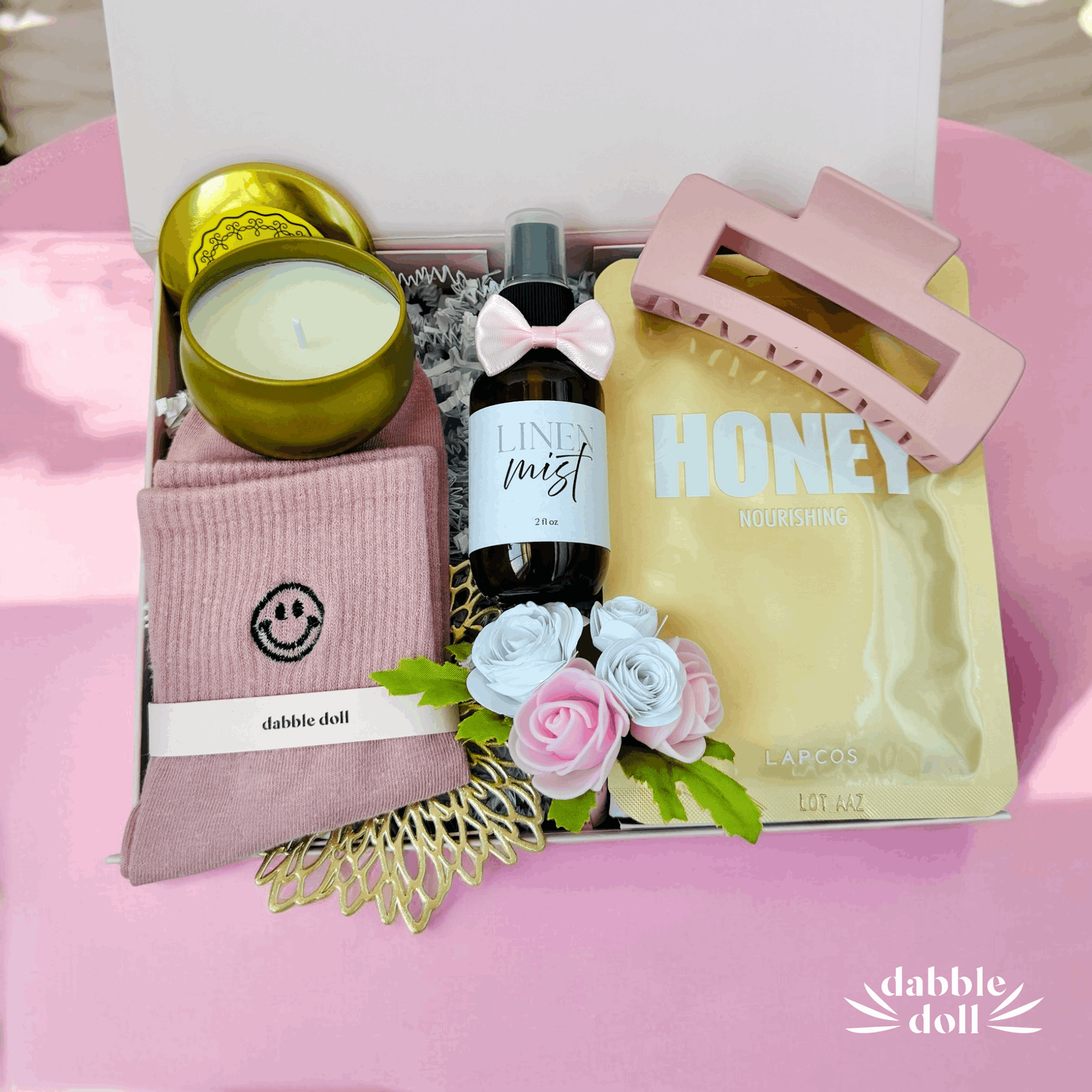 Dabble Doll gift box with unique relaxation gift ideas including candle, linen mist, hair clip, nourishing honey mask, and cozy socks