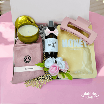 Dabble Doll gift box with unique relaxation gift ideas including candle, linen mist, hair clip, nourishing honey mask, and cozy socks