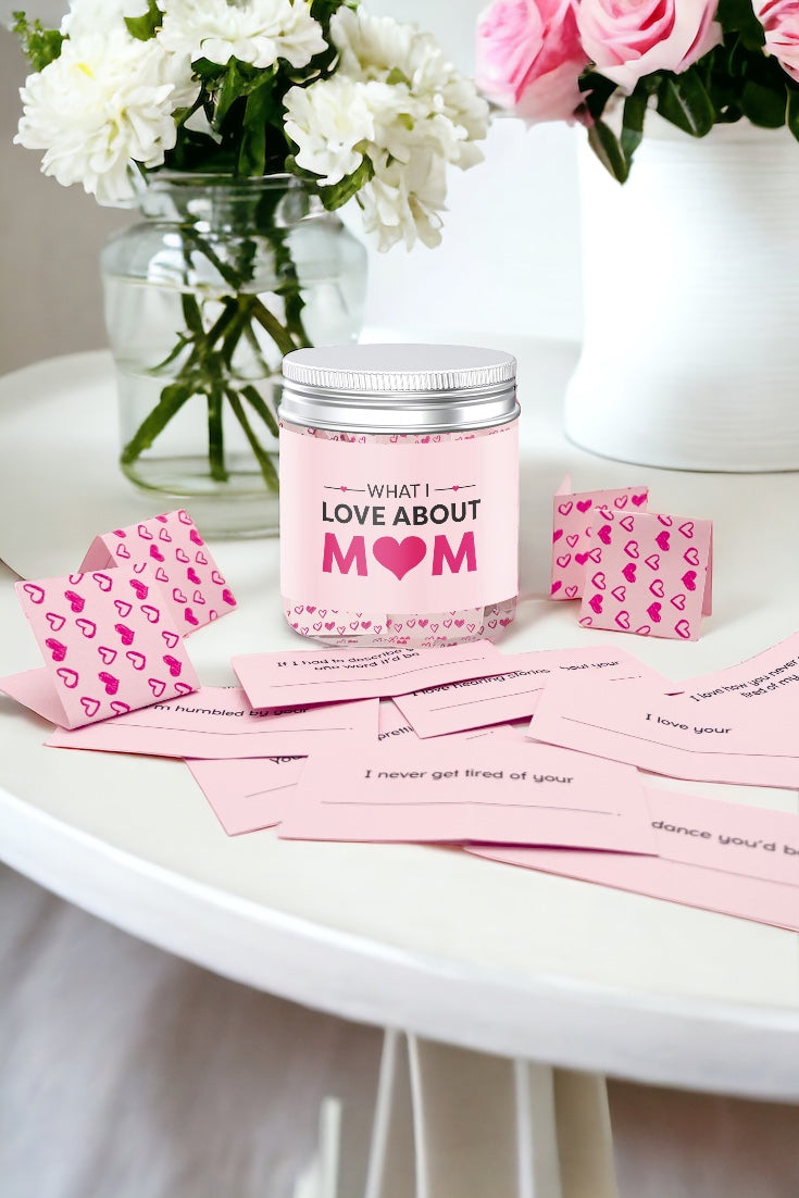 What I love about mom jar with pink heart notes on white table next to floral vases