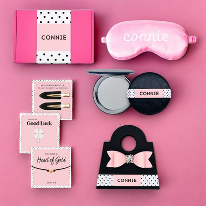 Pink gift box for women containing a sleep mask, hair clips, and beauty products