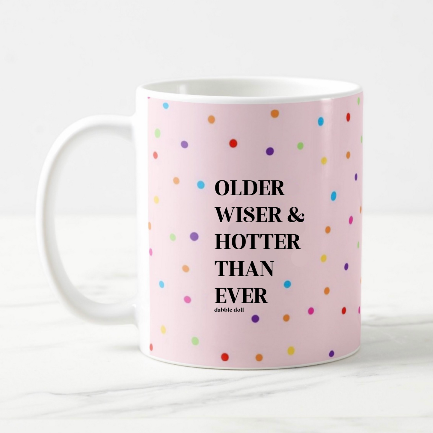Funny coffee mug by Dabble Doll with colorful polka dots and the phrase Older Wiser & Hotter Than Ever
