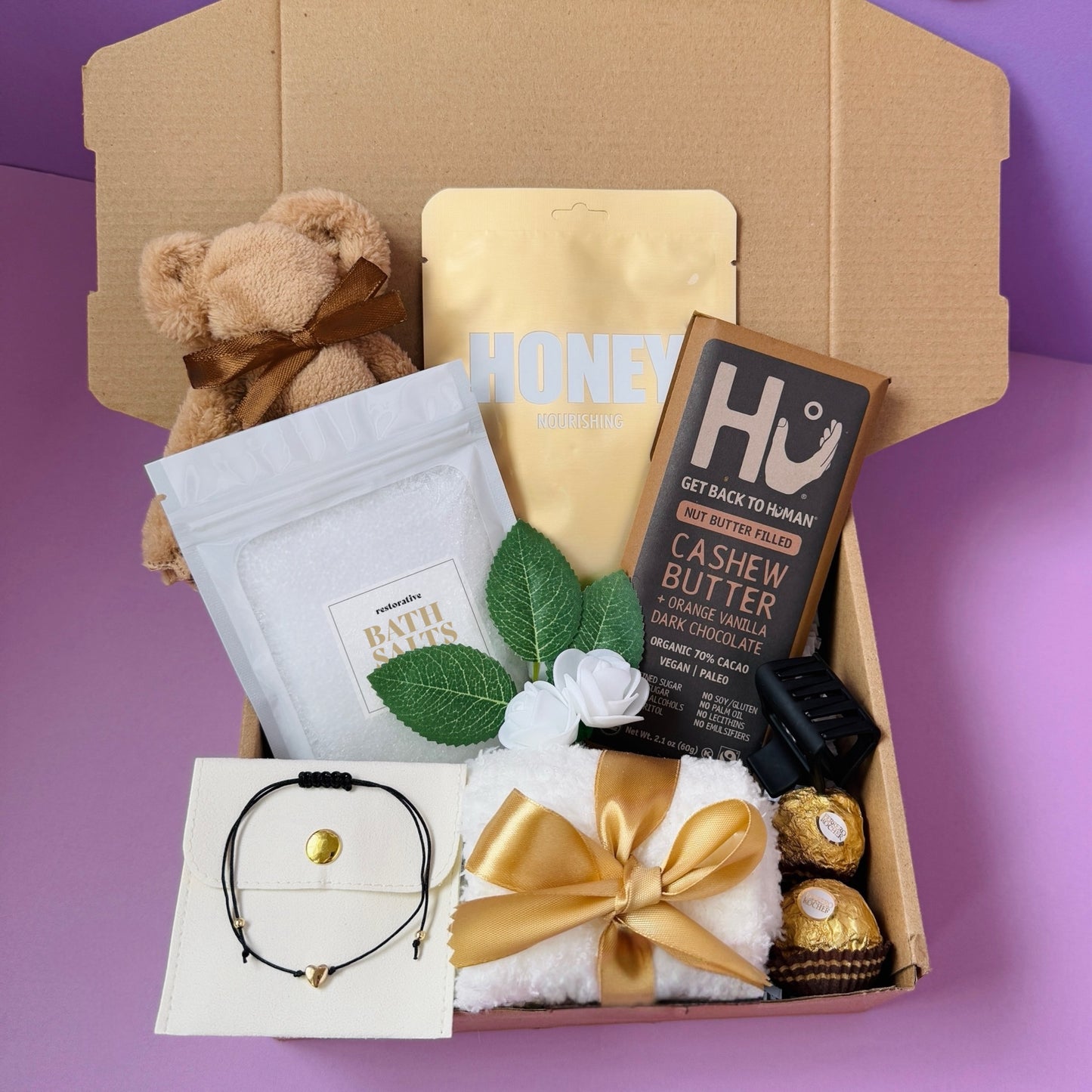 Dabble Doll gift box for girls featuring a teddy bear, chocolate, and relaxation items in a pink themed packaging