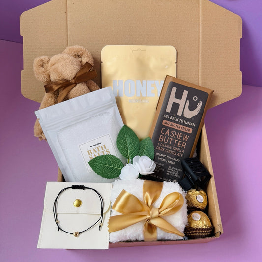 Dabble Doll gift box for girls featuring a teddy bear, chocolate, and relaxation items in a pink themed packaging