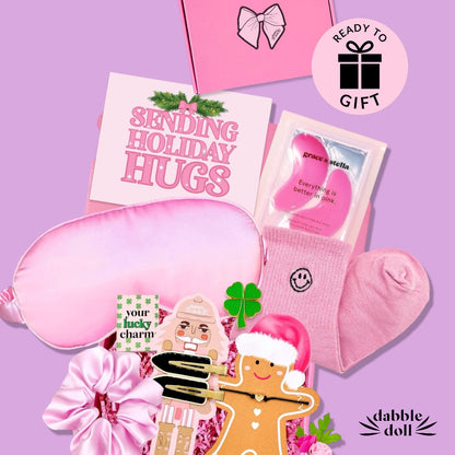 Pink gift box from Dabble Doll for girls featuring a sleep mask, cozy socks, and fun holiday essentials