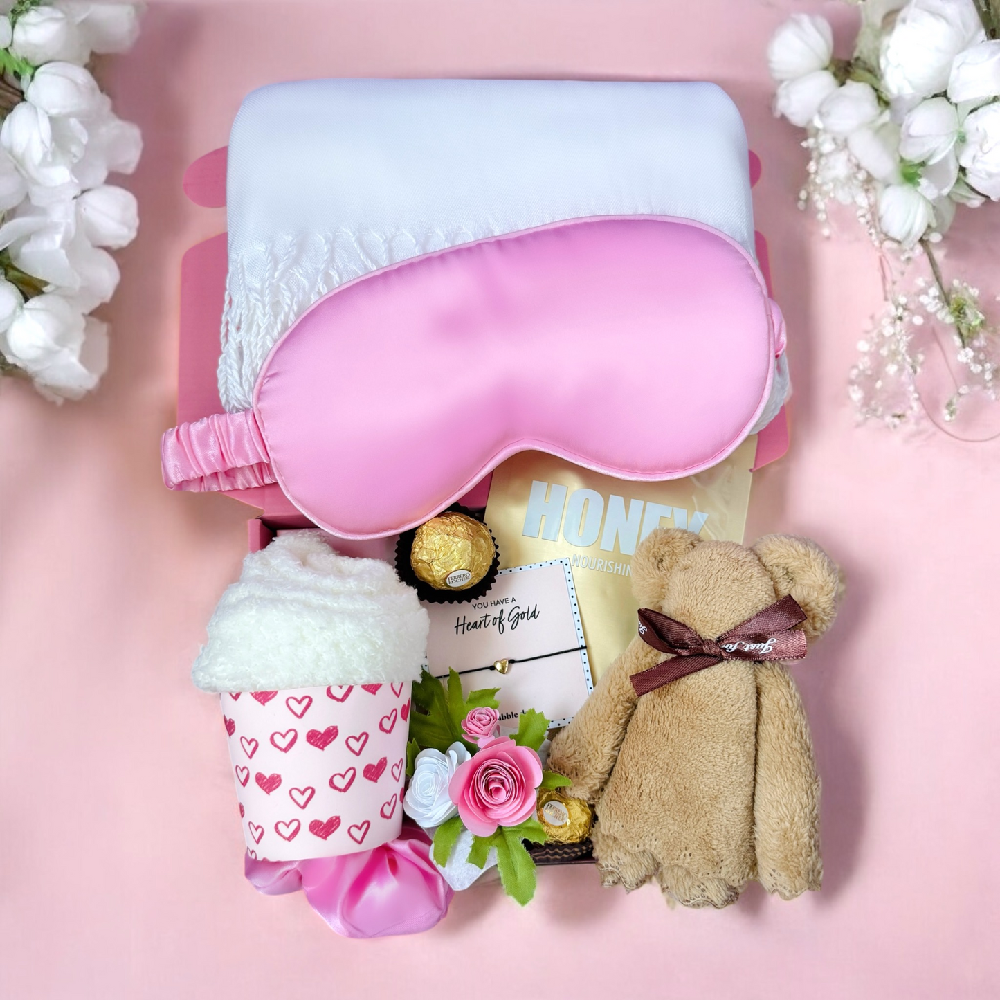 Gift box for women containing a pink sleep mask, teddy bear, and a romantic cup filled with treats