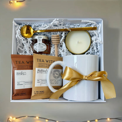 Elegant gift box for women featuring a white mug, tea sachets, honey, and a candle