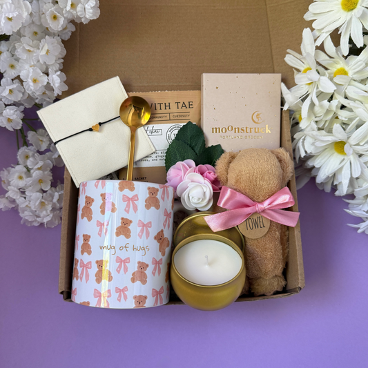 Dabble Doll gift in box featuring a candle, teddy bear, mug, and decorative items for a thoughtful present