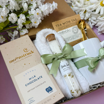Dabble Doll gift in box featuring milk chocolate, tea, and a decorative mug and spoon
