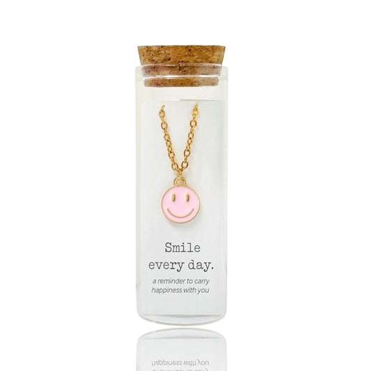 Gold necklace with a pink smiley face pendant in a glass bottle by Dabble Doll