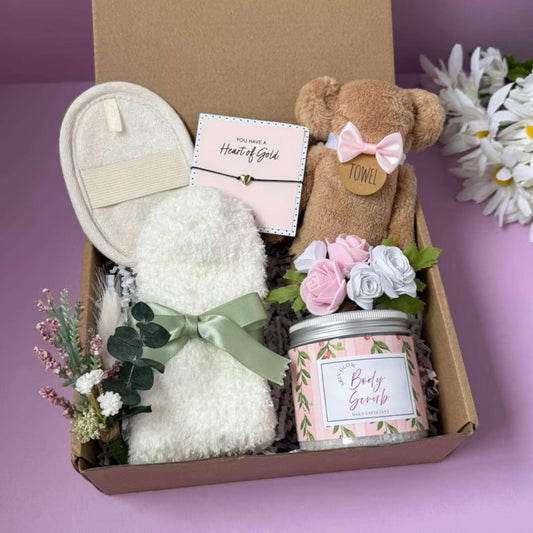 Dabble Doll relaxation gift box for women with plush towel, body scrub, soft slippers, floral decor, and heart bracelet