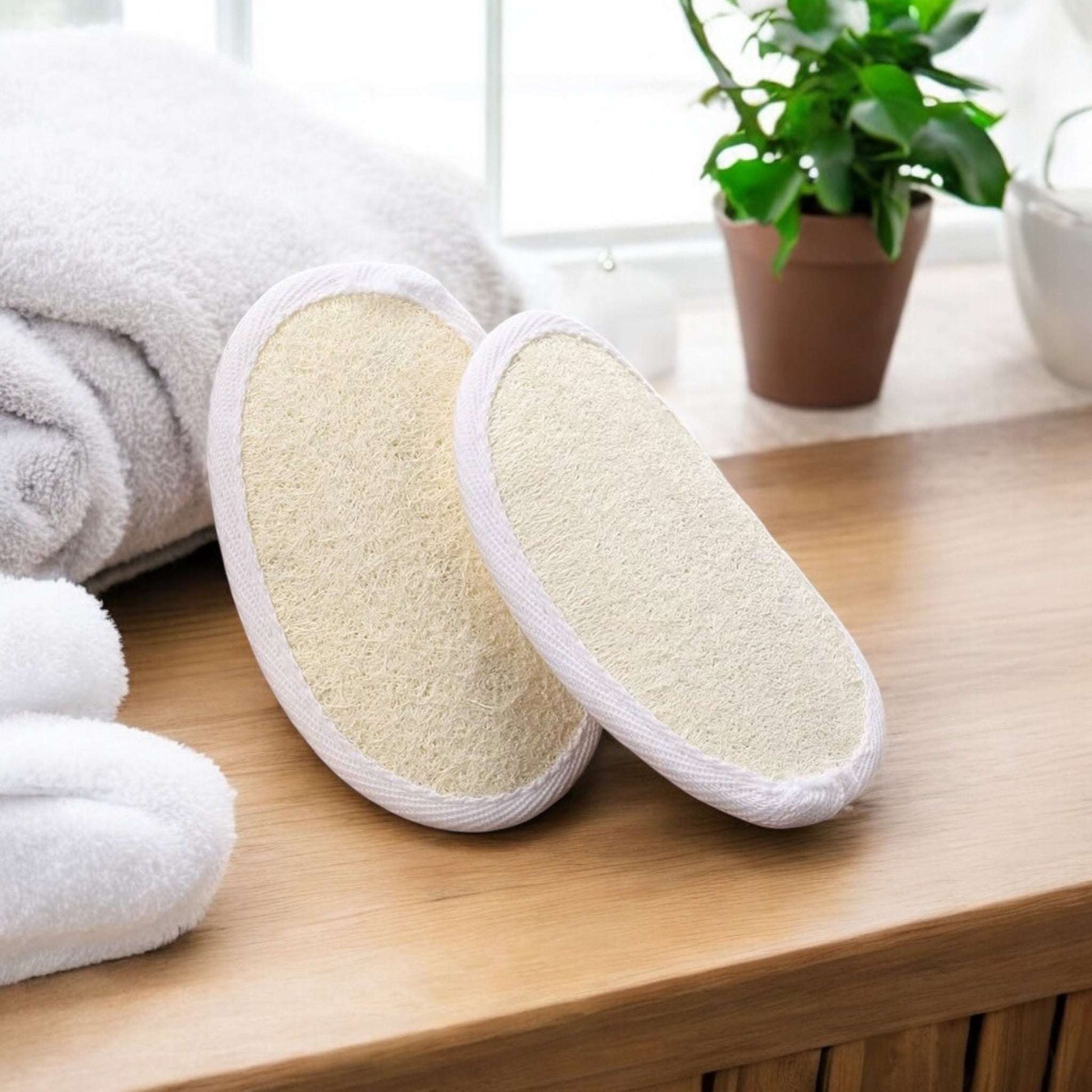 Dabble Doll exfoliating pad set on a wooden surface with towels and plants in the background
