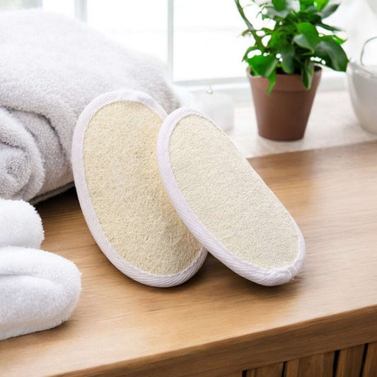 Dabble Doll exfoliating pad set on a wooden surface with towels and plants in the background