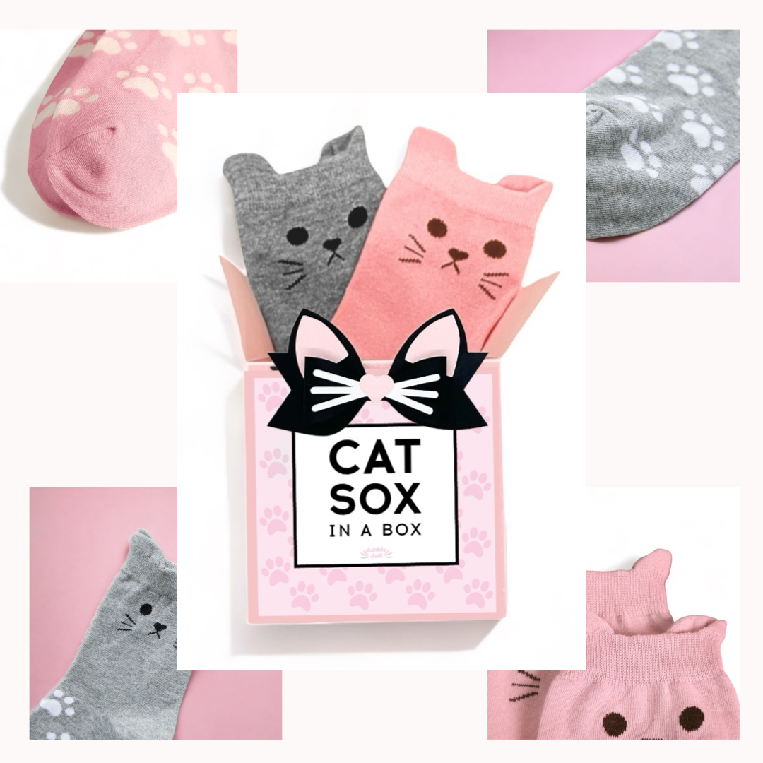 Dabble Doll Cat Socks in a Box featuring playful cat designs in gray and pink